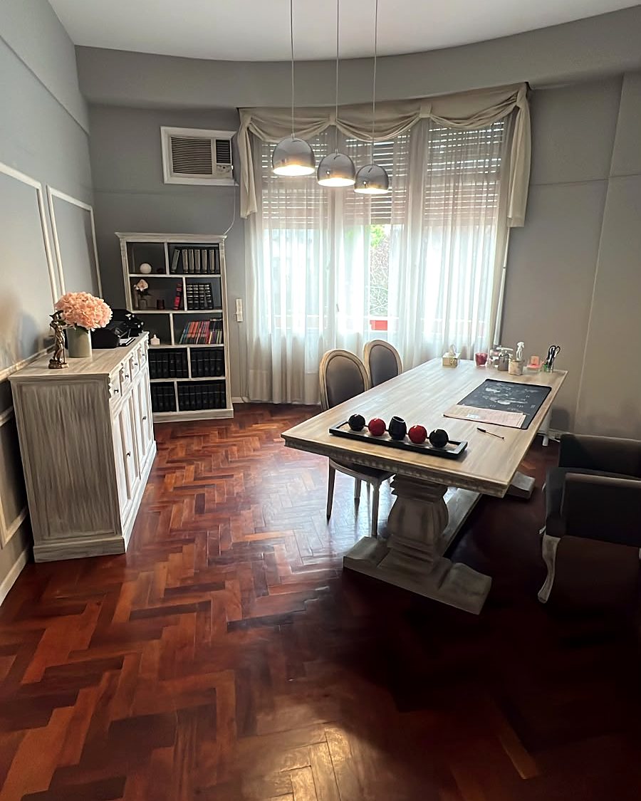 Sala de reuniones del estudio, con mesa de madera y biblioteca
